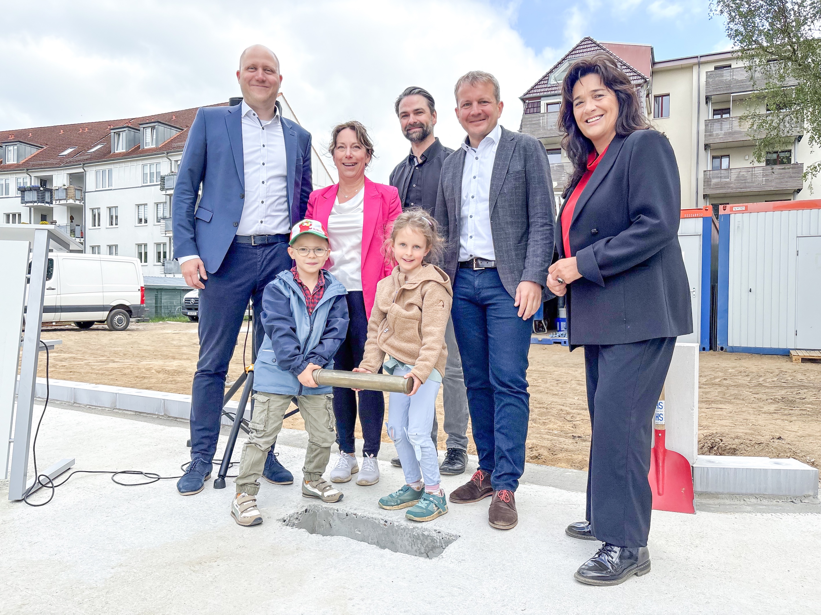 Kinder und offzielle Gäste betonieren die traditionelle Zeitkapsel ein Einbetonieren der Zeitkapsel